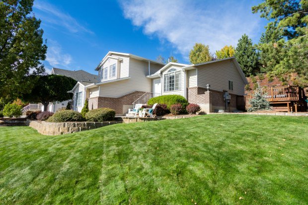 Beautiful suburban house with a manicured lawn, framed by trees and blue sky.